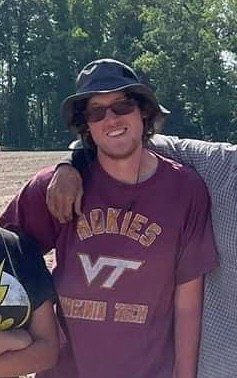 Young man wearing hat and Virginia Tech t-shirt in field