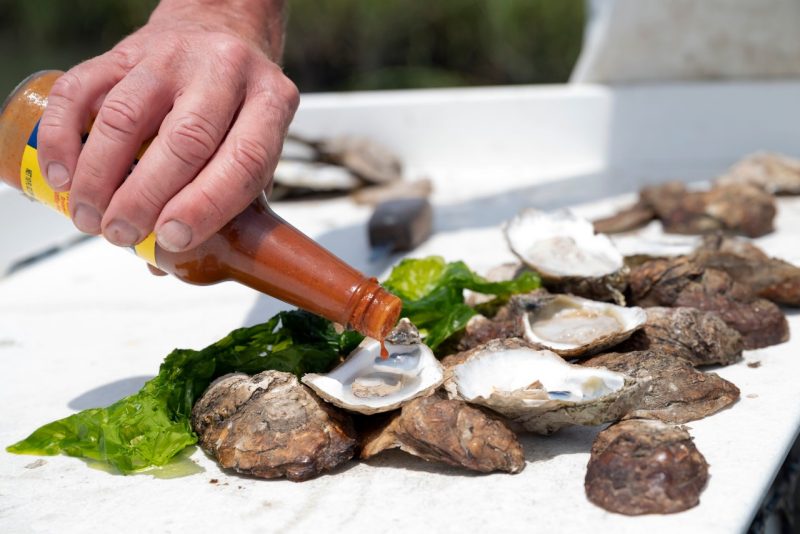 Sauce being added to grilled oysters