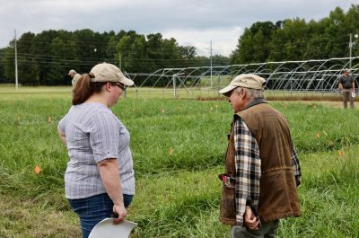 A woman in cap discusses the field plots with a man in cap.