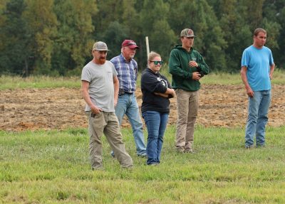 A group of four men and a woman stand in the field during a field day presentation.