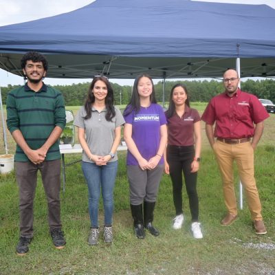 A group of students stand in front of a tent during a field day activity. 