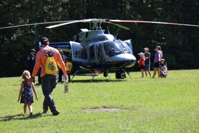 A man and a small child move toward a Virginia State Helicopter that has landed