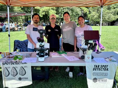 Four people stand behind a table displaying microscopes