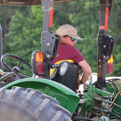 Woman on tractor wearing ball cap and sunglasses